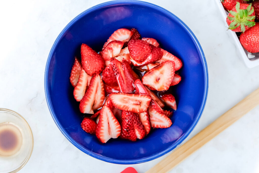 Sliced strawberries in a blue mixing bowl.