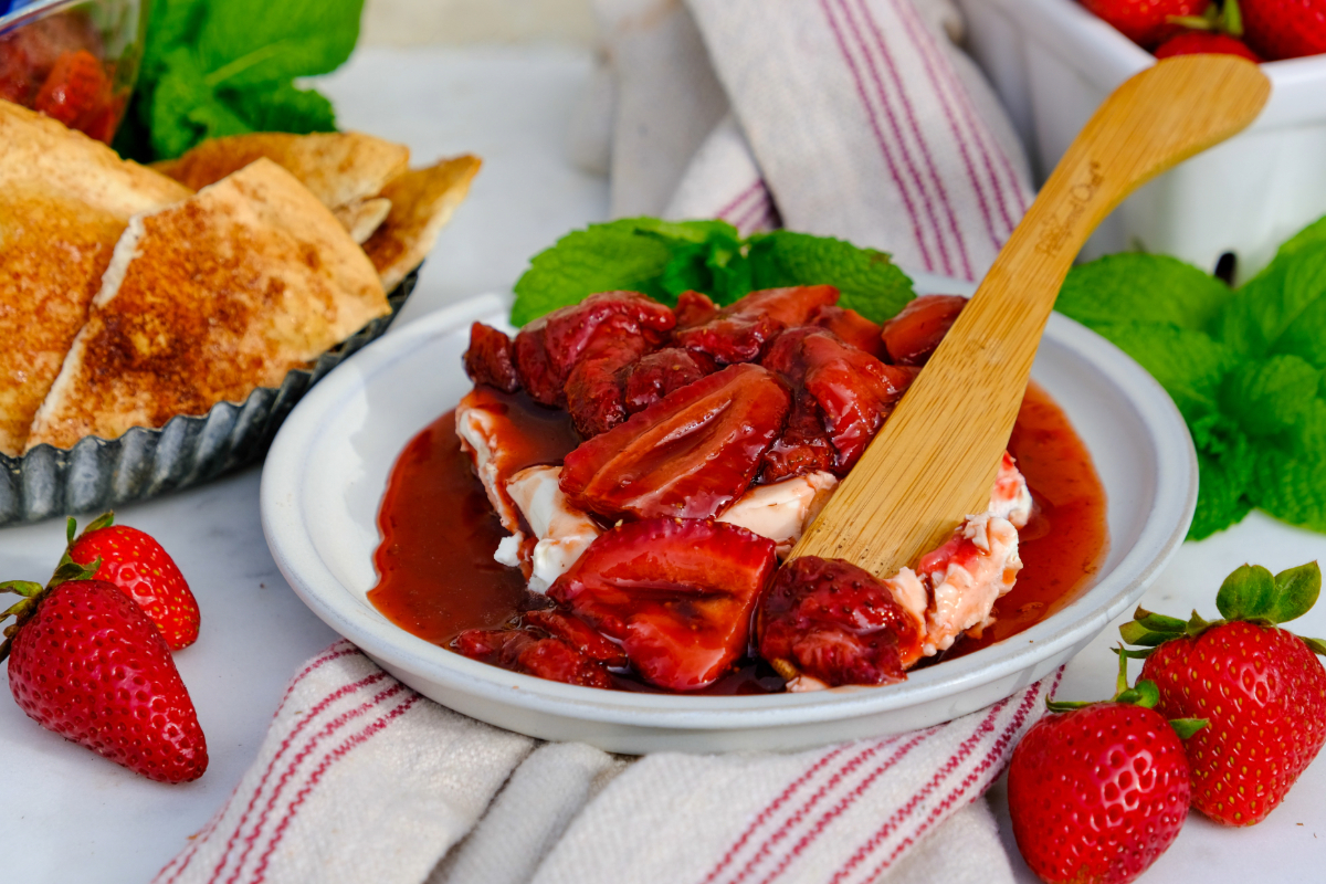 Cream cheese on a white plate topped with roasted strawberries.