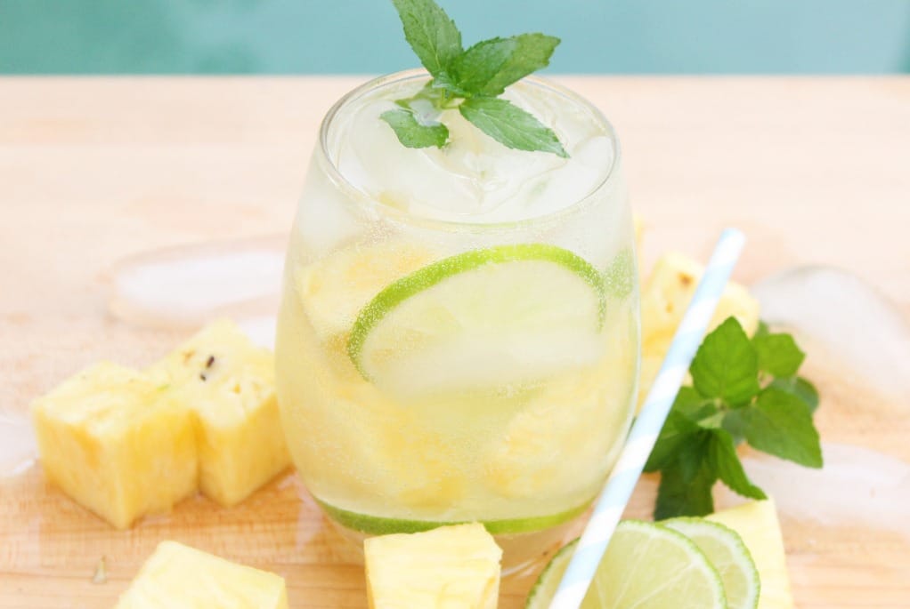 clear glass with chunks of pineapple around a pineapple mojito cocktail. 