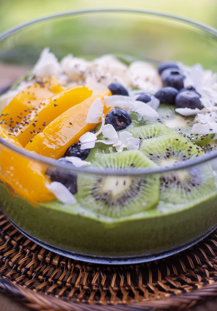 chia pudding with slices of mango and fresh blueberries in a clear bowl. 