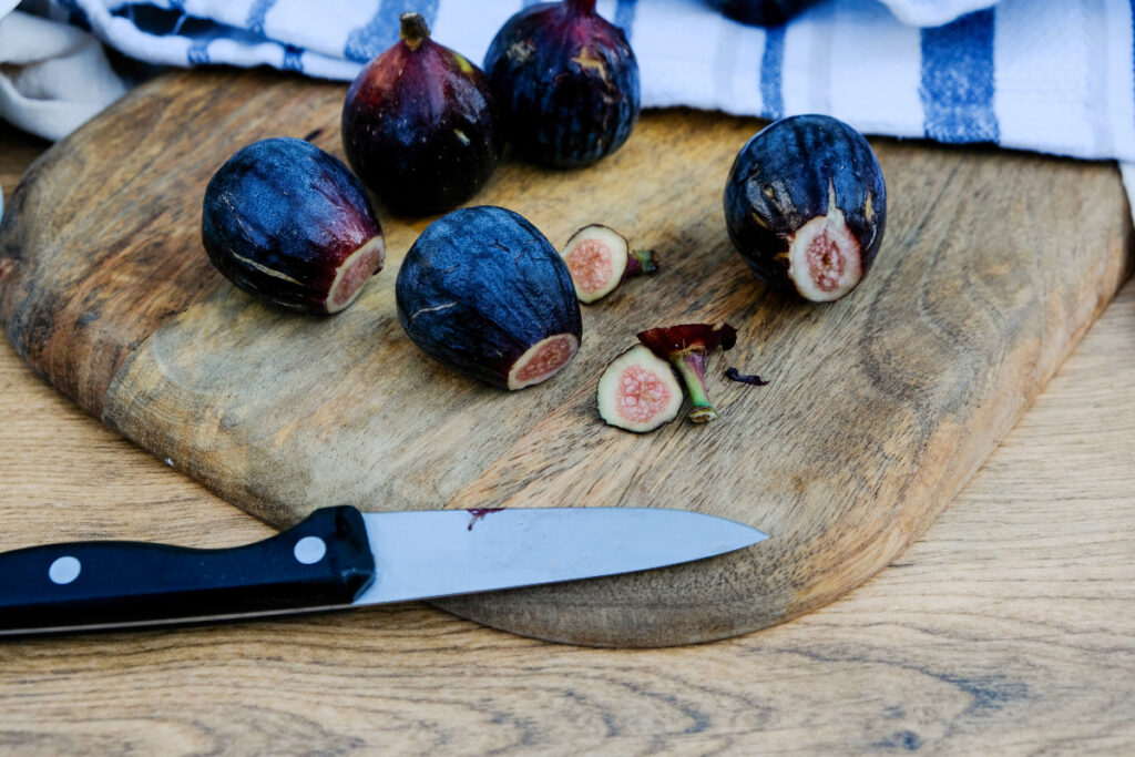 Clean figs on a cutting board with the stems removed.