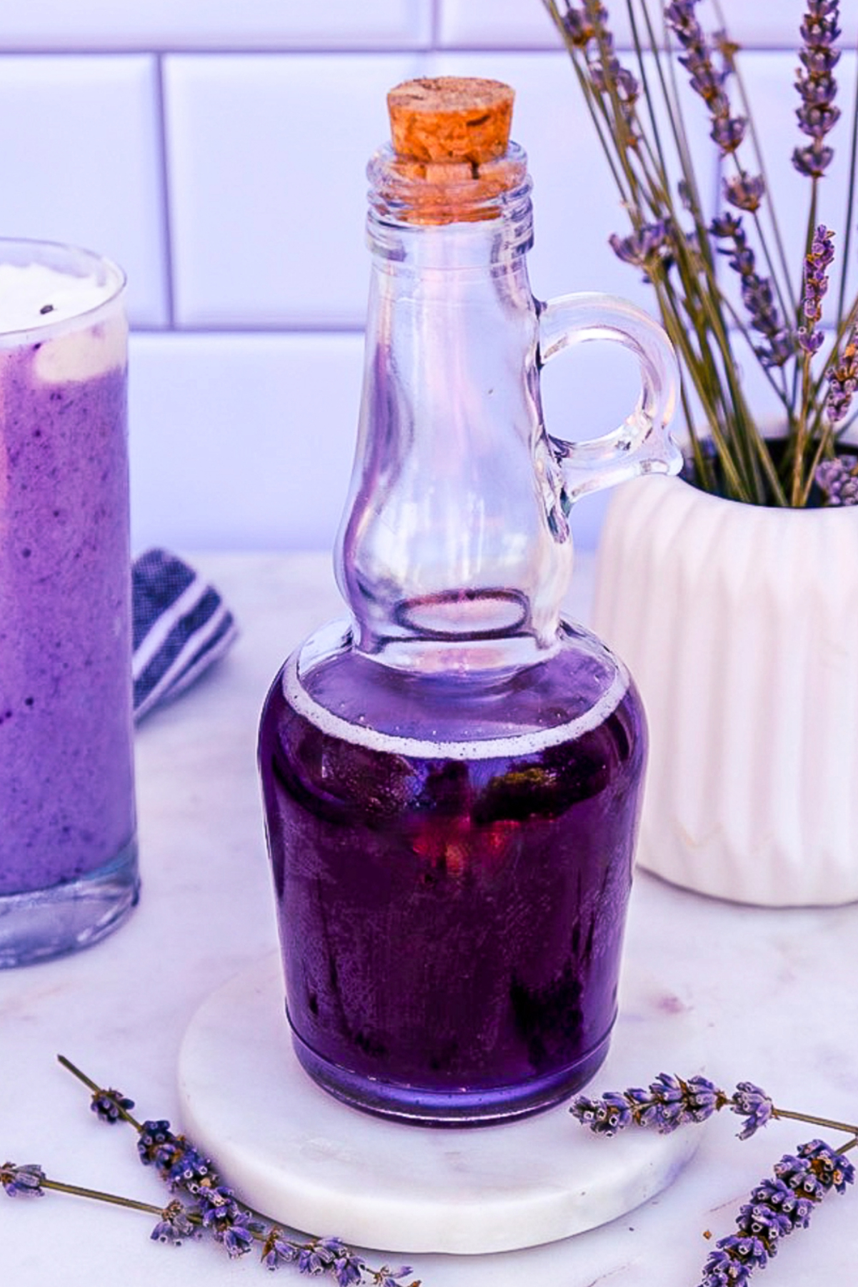 Homemade lavender syrup in a small clear pouring jug.