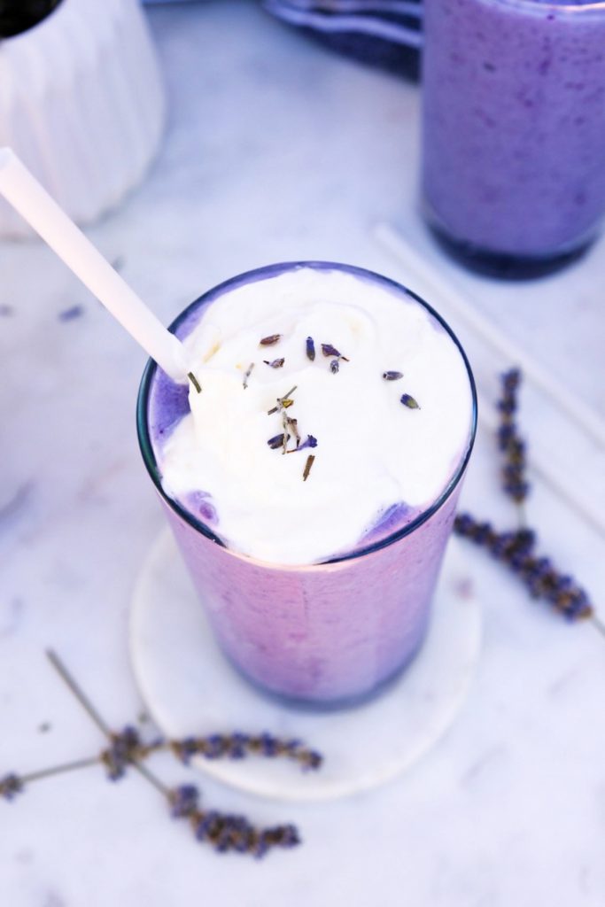 Top view of blended frappuccino topped with whipped cream and lavender buds.