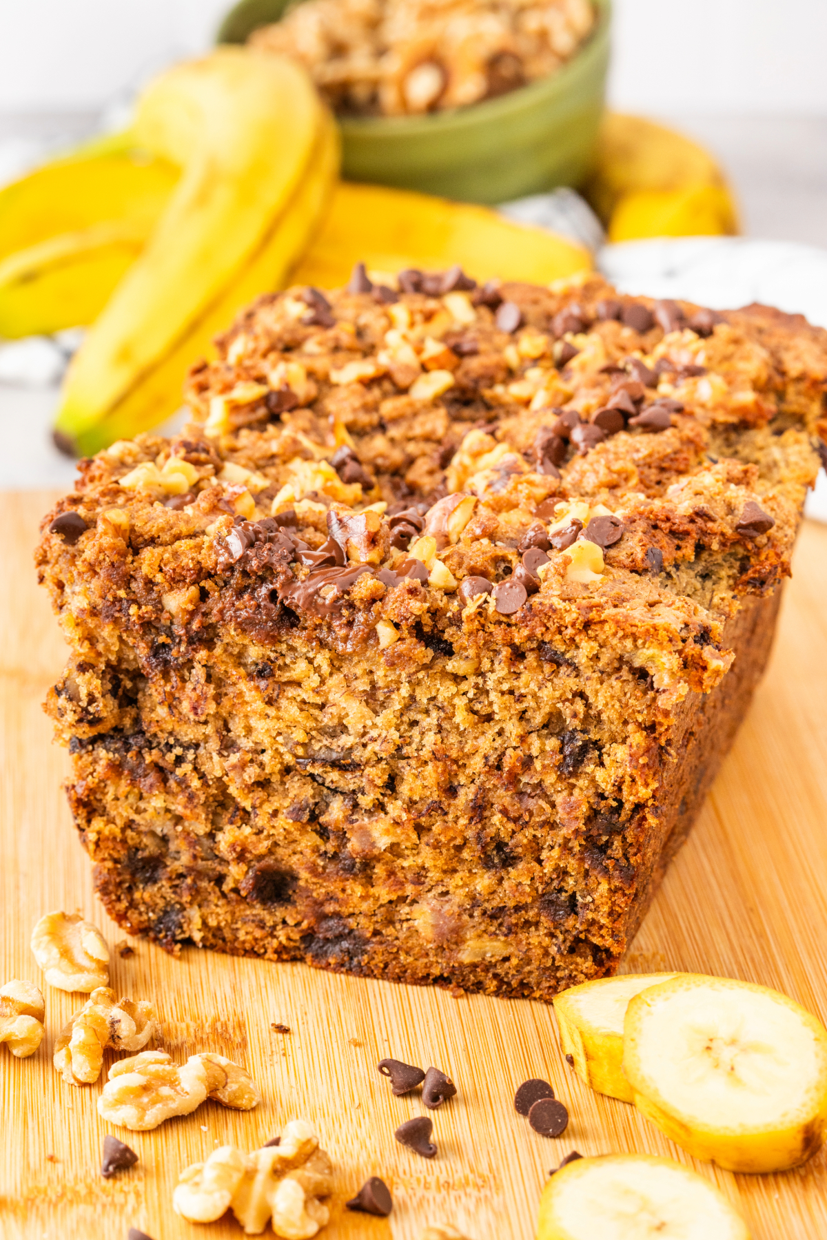 A loaf of banana bread with streusel topping on a brown cutting board. 