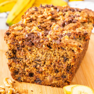 Banana bread with streusel topping on a tan cutting board.