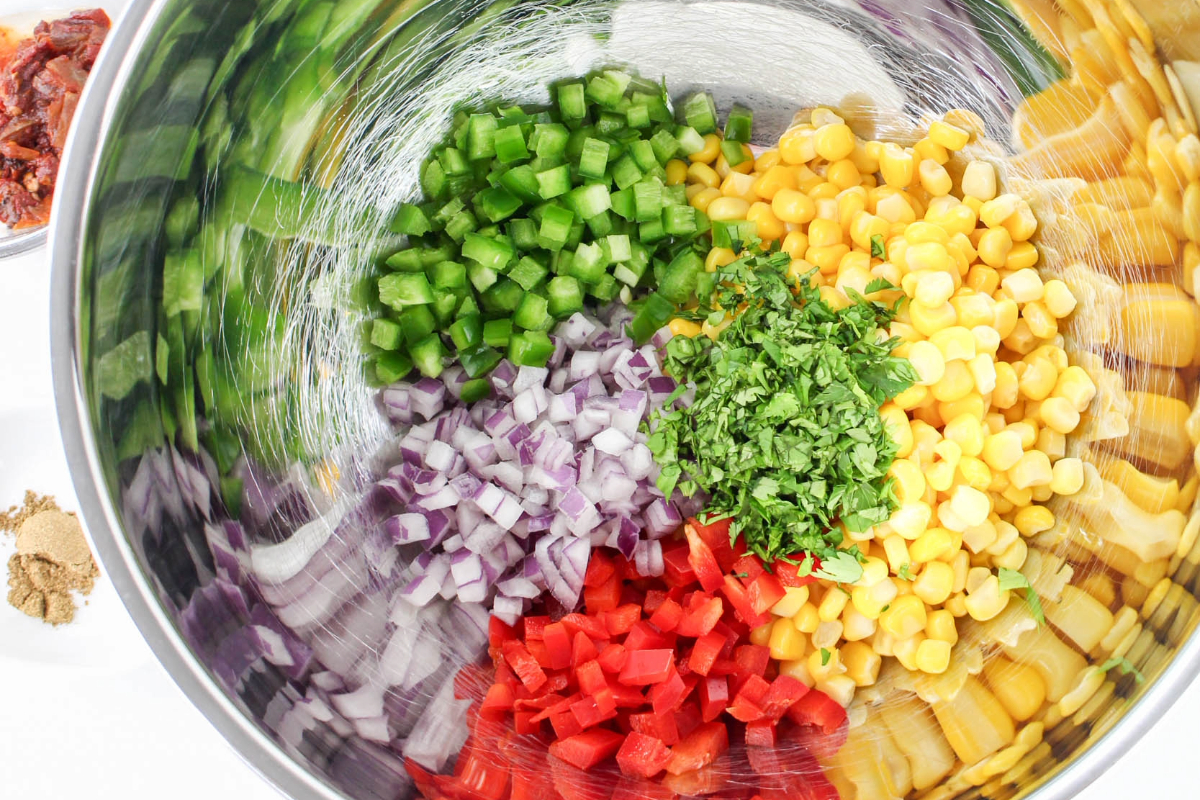 Ingredients to make corn salsa in a mixing bowl before combining. 