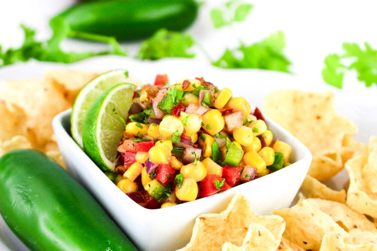 Corn dip with jalapeños in a white bowl. 