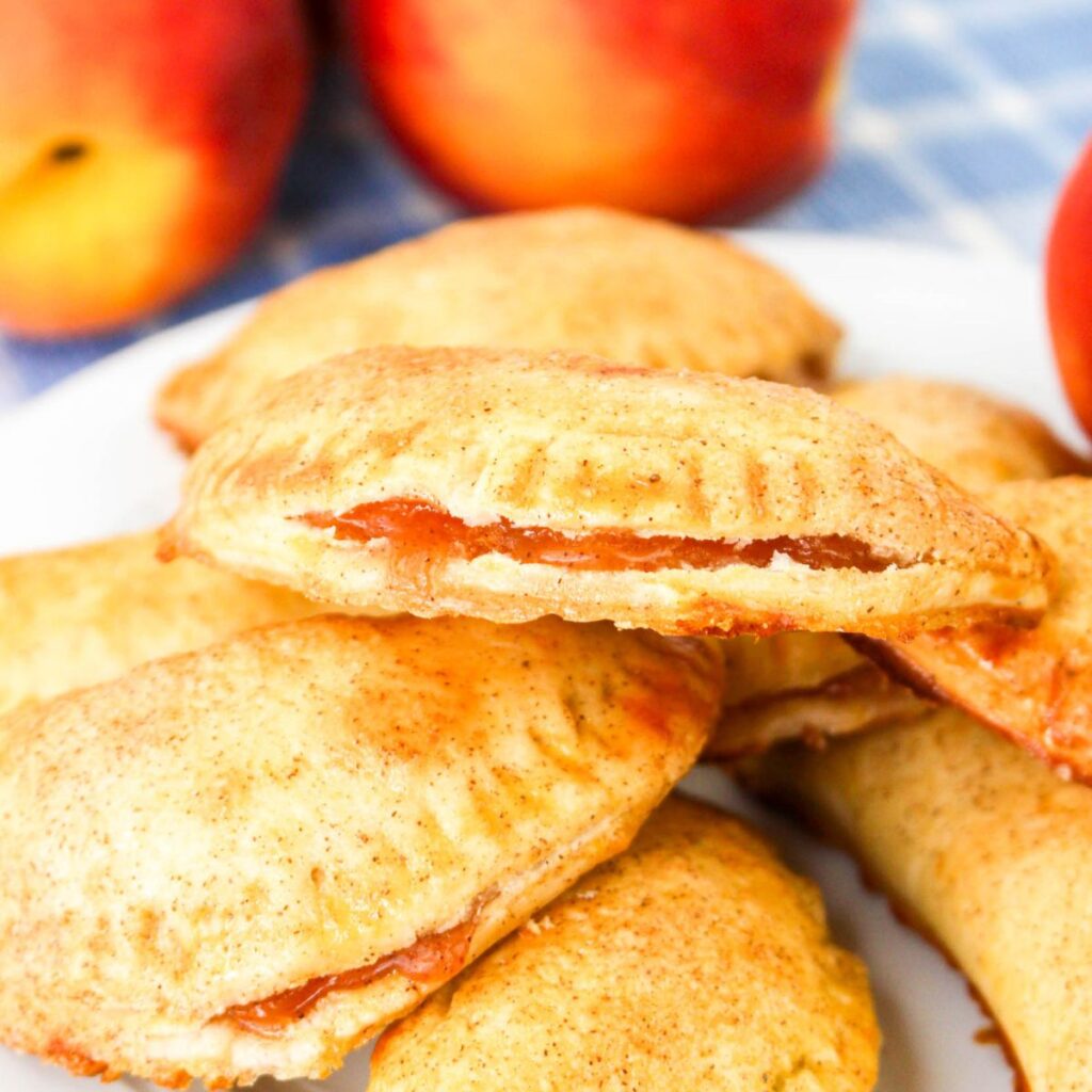 Peach hand pies stacked on a plate.