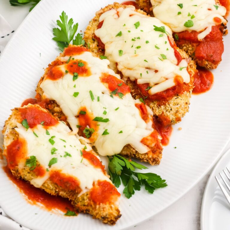 Serving platter with four pieces of parmesan crusted chicken breasts on it.